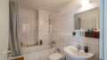 Weiß gefliestes Badezimmer mit Wanne